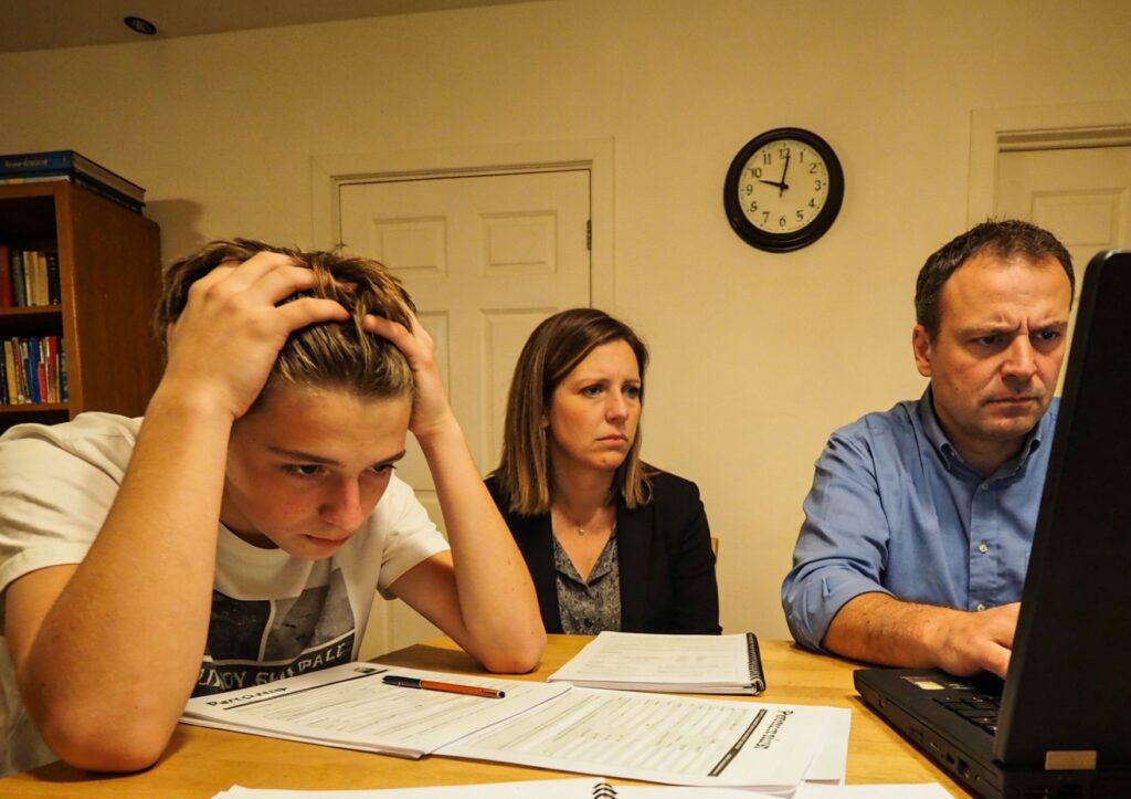 Un lycéen français et ses parents discutant de la procédure Parcoursup avec une expression préoccupée devant un ordinateur.